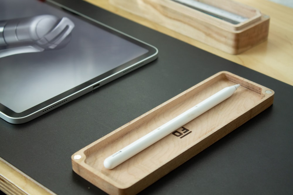 a wooden tray with a pen and a tablet