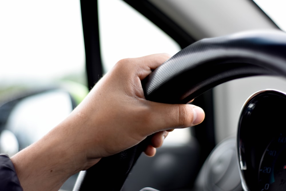 a person holding the steering wheel of a car