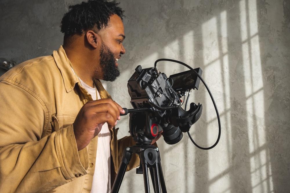 a man standing next to a camera on a tripod