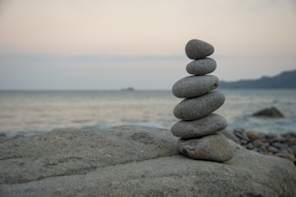 a stack of rocks sitting on top of a rock near the ocean