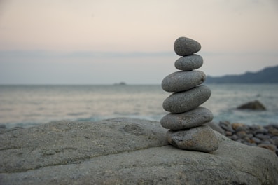 a stack of rocks sitting on top of a rock near the ocean