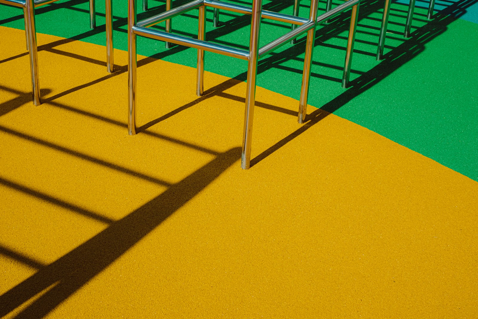 A stainless climbing frame over yellow and green rubber safety surfacing