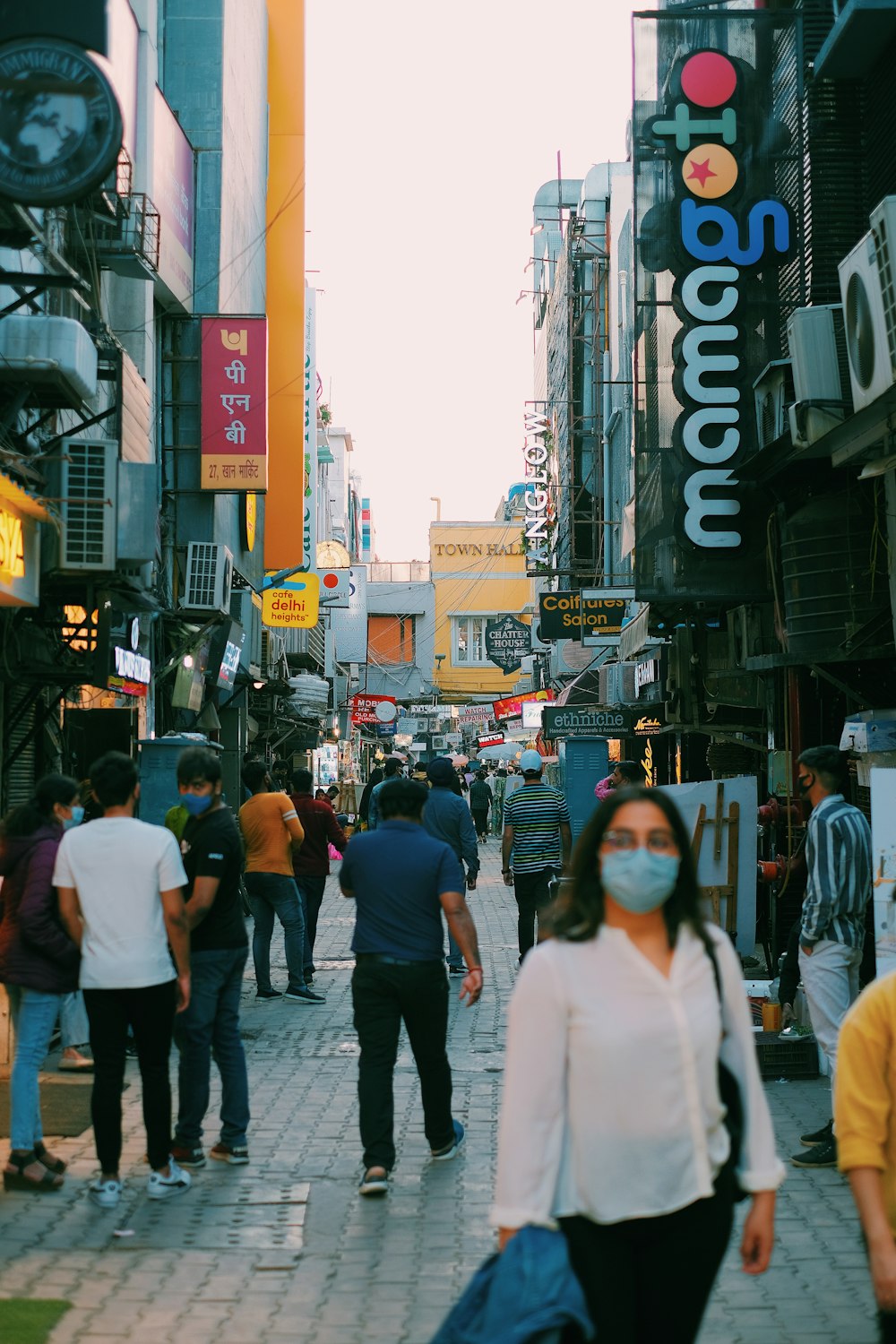 a group of people walking down a street next to tall buildings