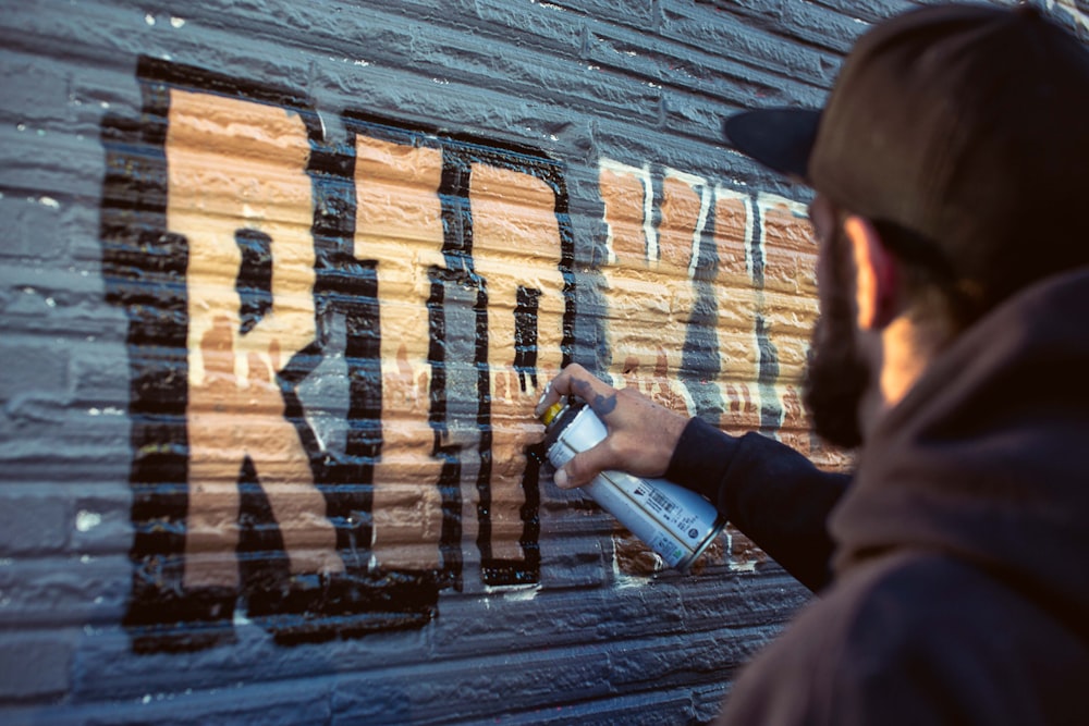 a man spray painting the side of a building