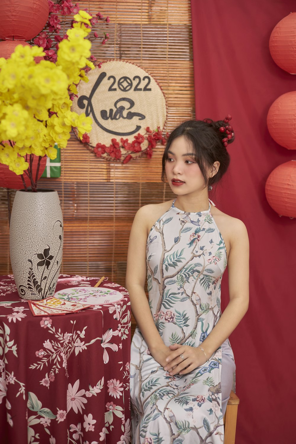 a woman sitting in front of a table with a vase of flowers