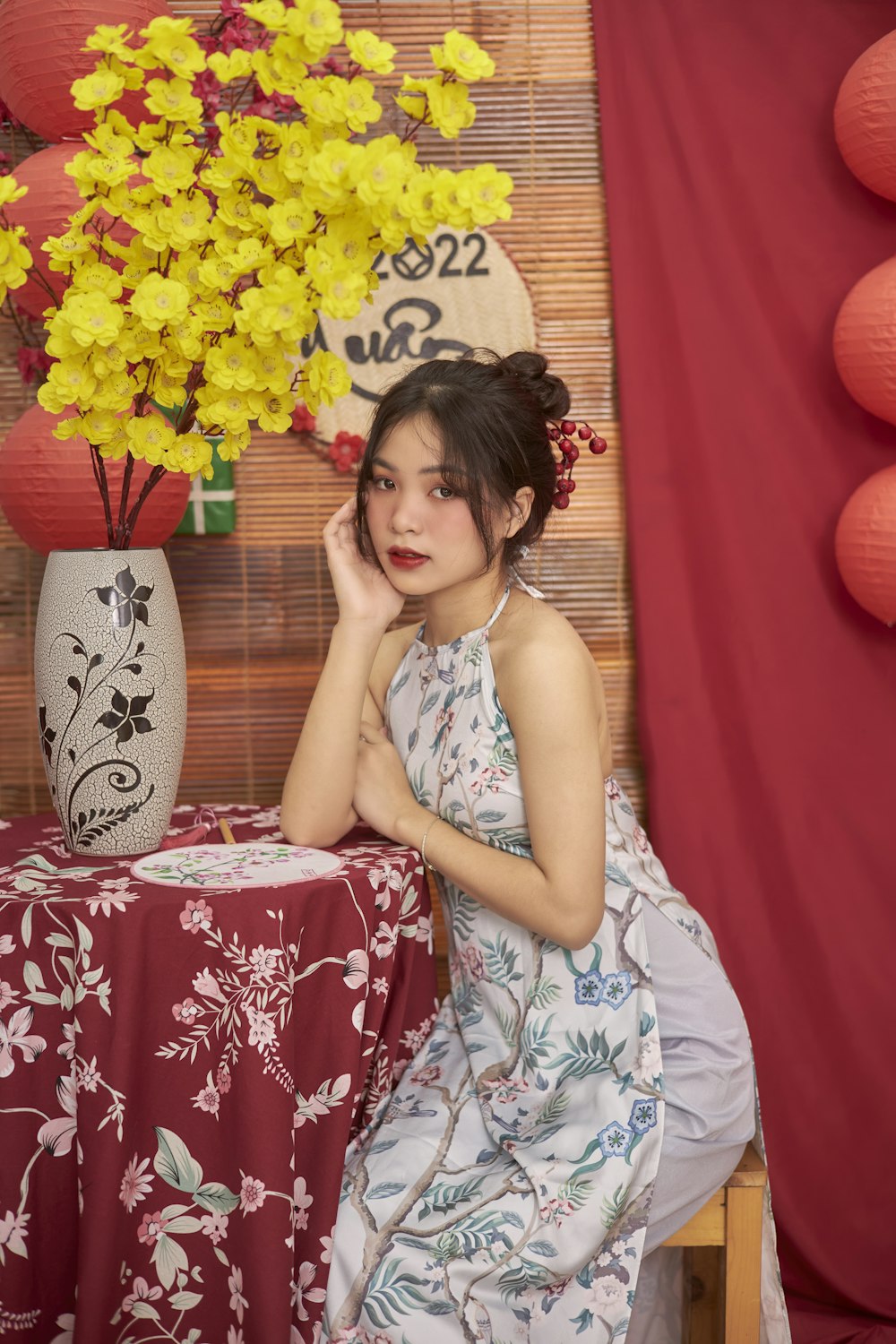 a woman sitting at a table with a vase of flowers