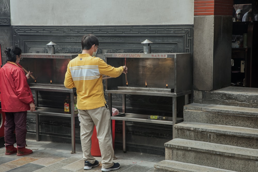 a man standing next to a metal stove on a sidewalk