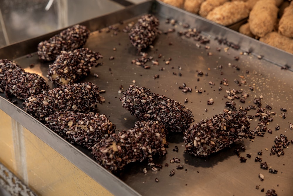 a metal tray filled with chocolate covered donuts