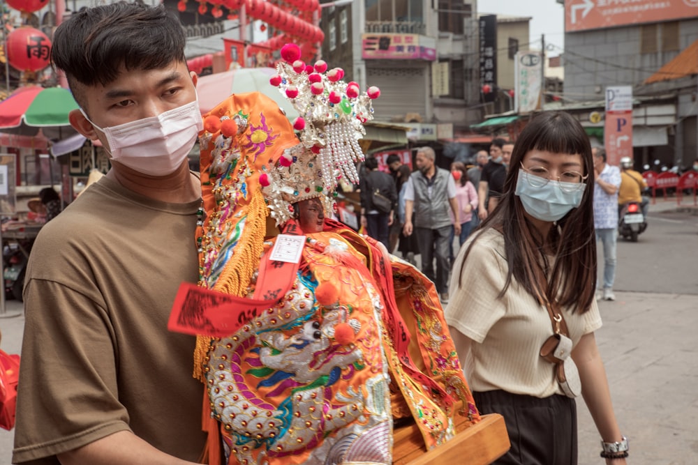 a man and a woman wearing face masks walking down a street