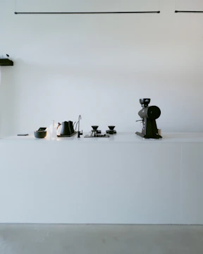 A minimalist kitchen counter featuring smart storage containers and a compact coffee maker in muted earth tones.
