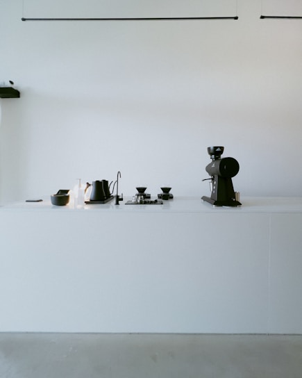 A cozy kitchen countertop featuring a sleek electric coffee maker with a steaming cup beside it.