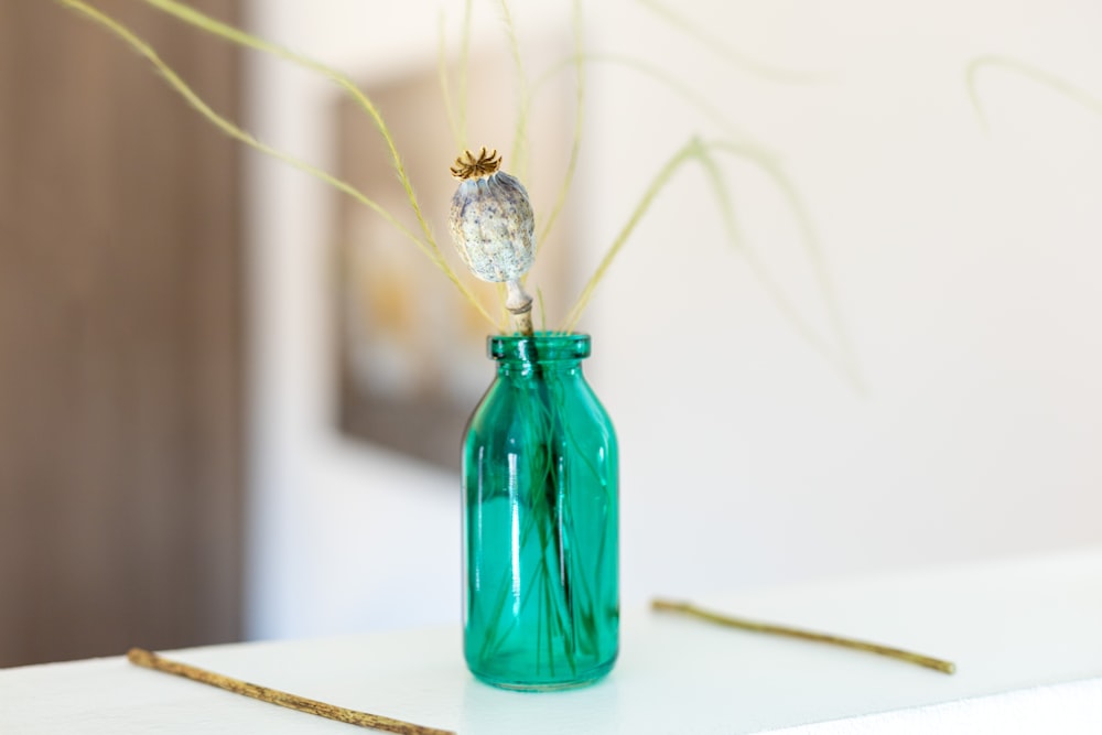 a green glass vase with a small bird on it