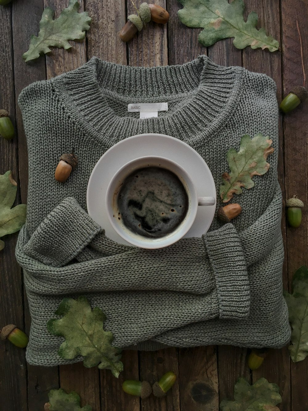 a cup of coffee and a sweater on a wooden table