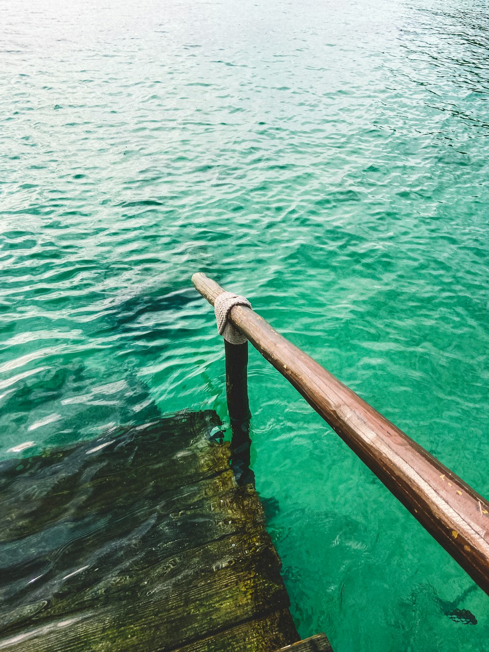 a wooden railing in the middle of a body of water