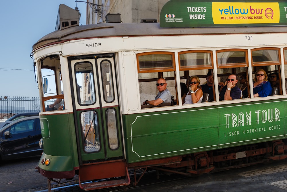 a group of people riding on the back of a green and white trolly