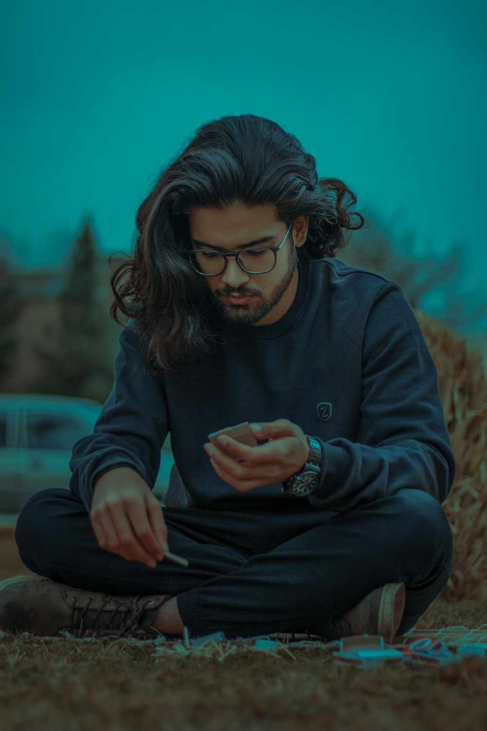 a man sitting on the ground looking at his cell phone