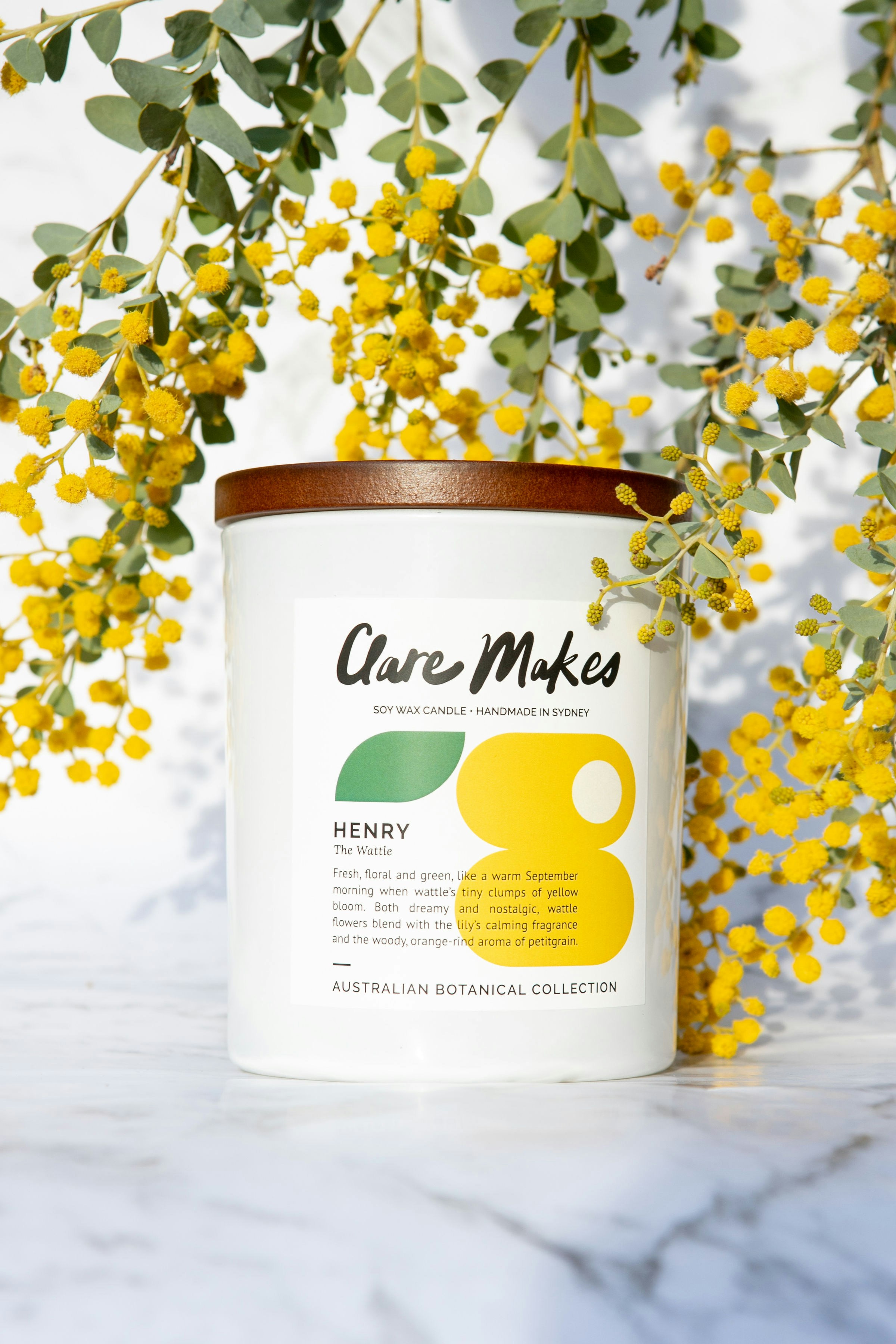 Minimalist soy wax candle in amber glass jar surrounded by dried botanicals on a white marble surface