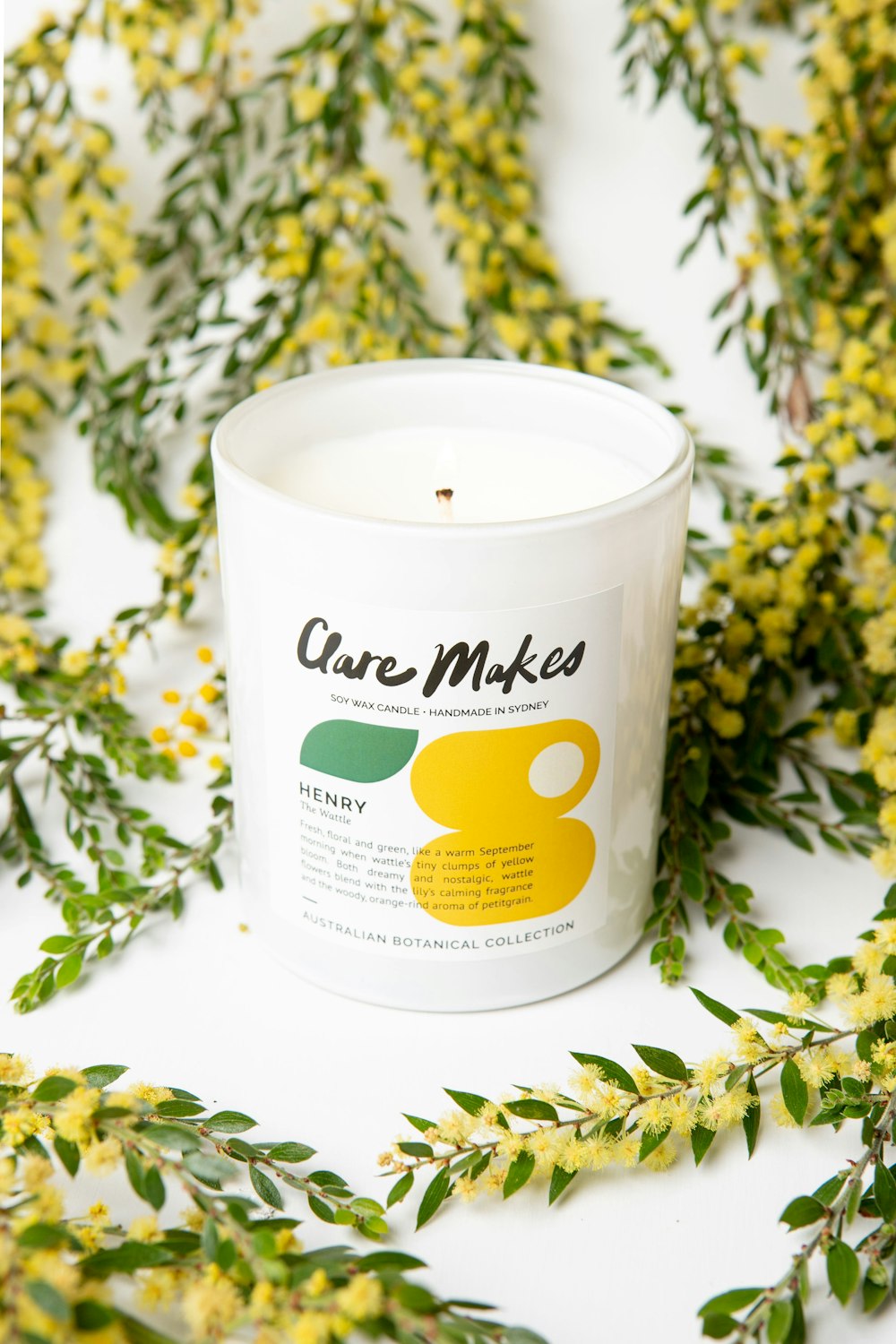 a white candle sitting on top of a table next to yellow flowers