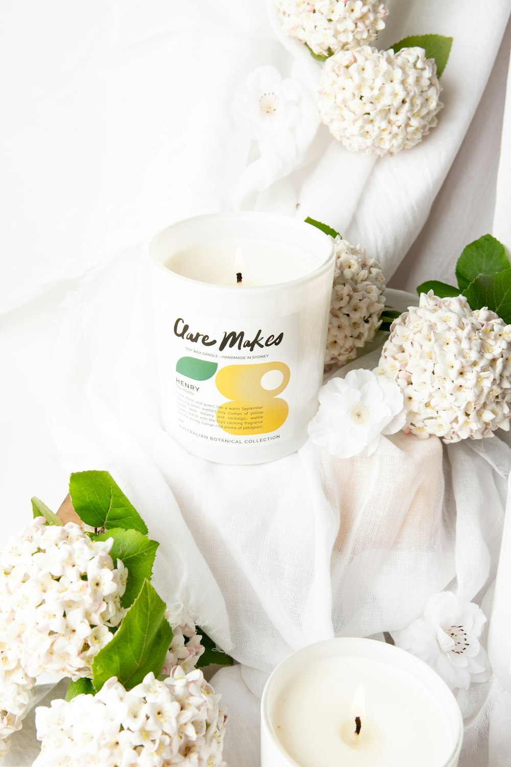 a candle and some flowers on a white cloth