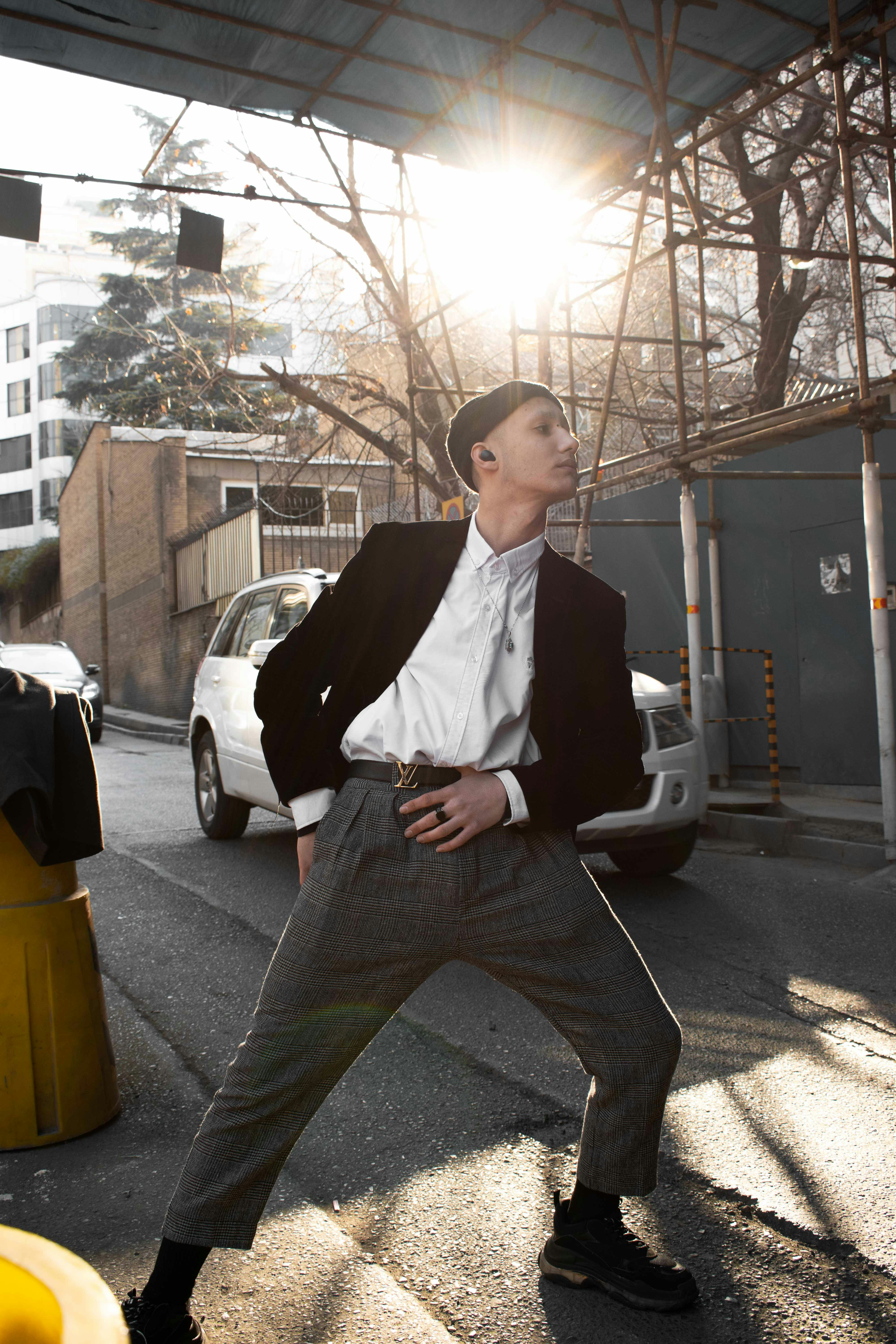 Young man in stylish outfit outdoors, bright natural light, urban environment