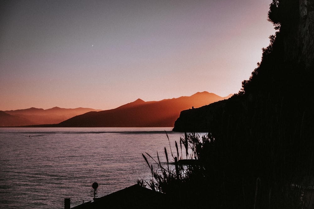 a lake with mountains in the background at sunset