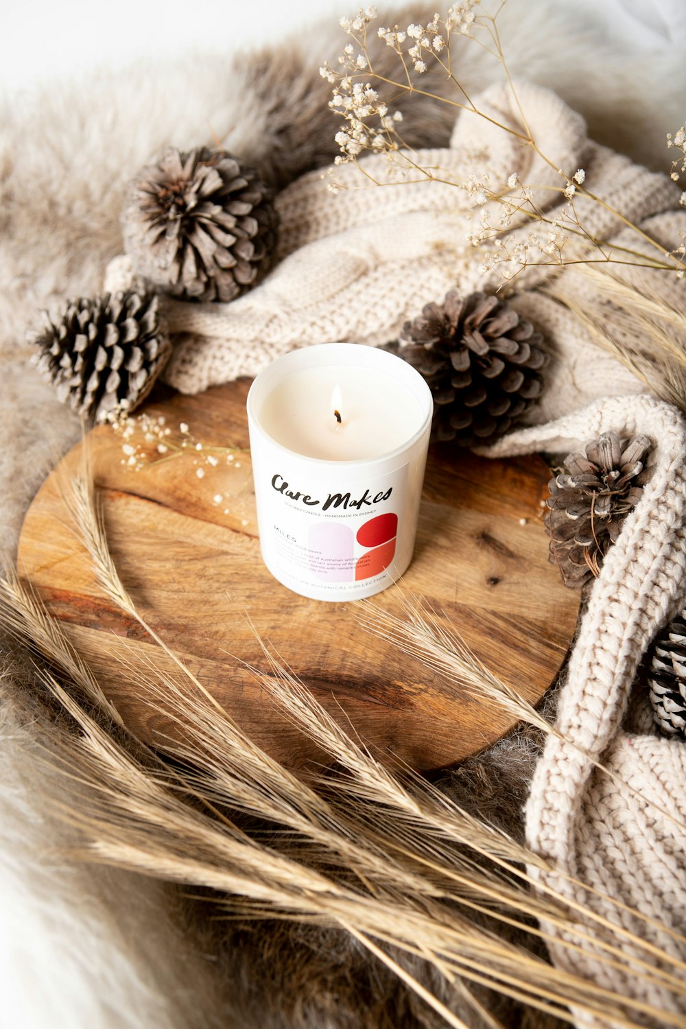 a white candle sitting on top of a wooden tray