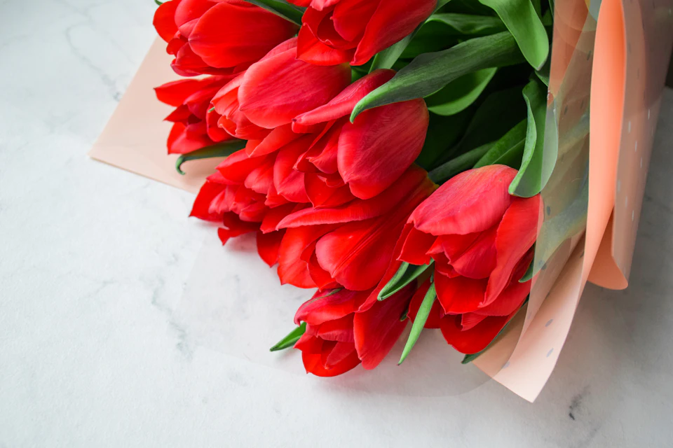Red tulips arranged in a loose style on a white marble countertop