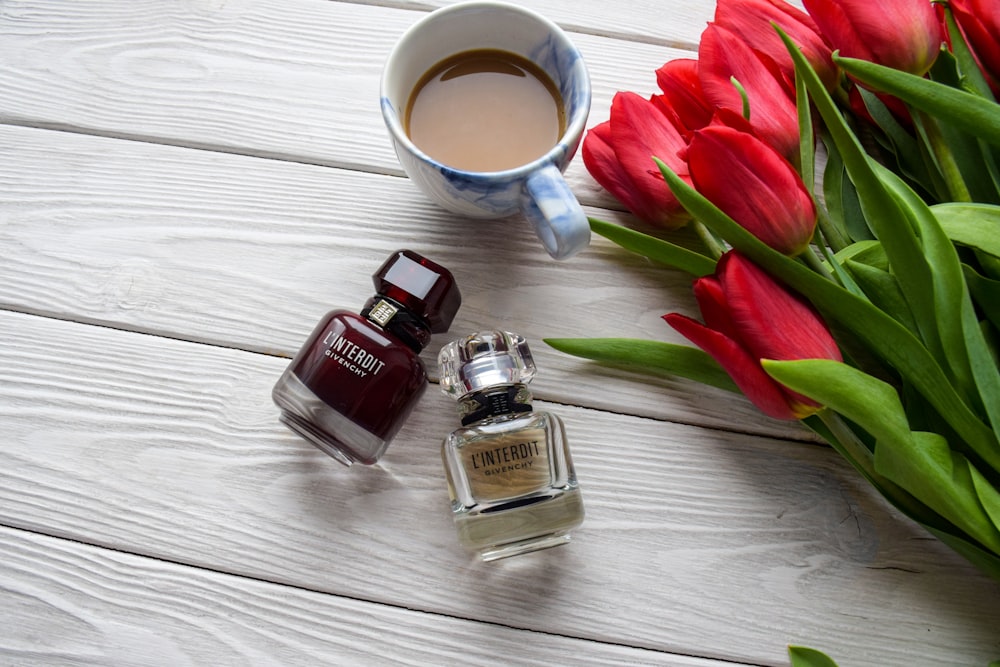 a cup of coffee next to a vase of red tulips