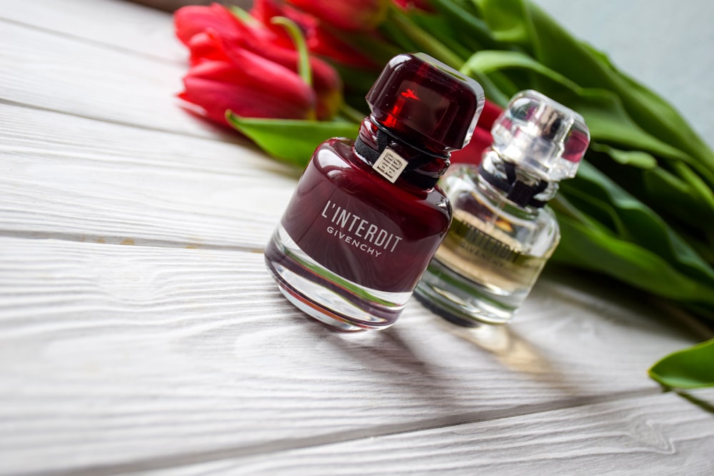 three bottles of perfume sitting on a table next to tulips