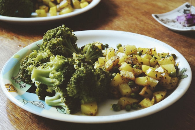 a plate of broccoli and potatoes on a table