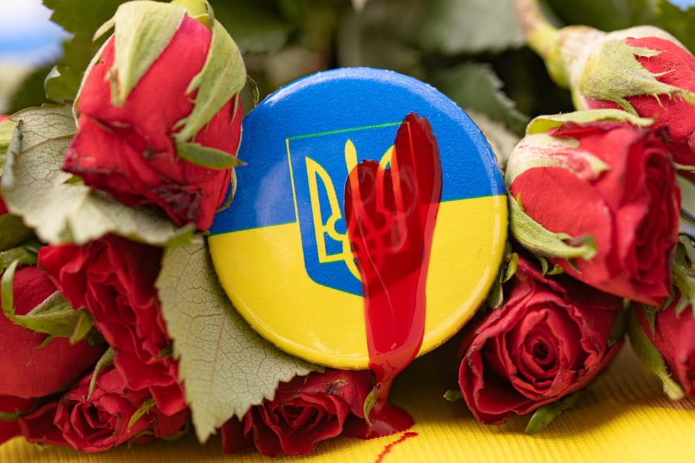 a bouquet of red roses and a blue and yellow button