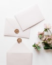 a white envelope with a wax stamp and some pink flowers