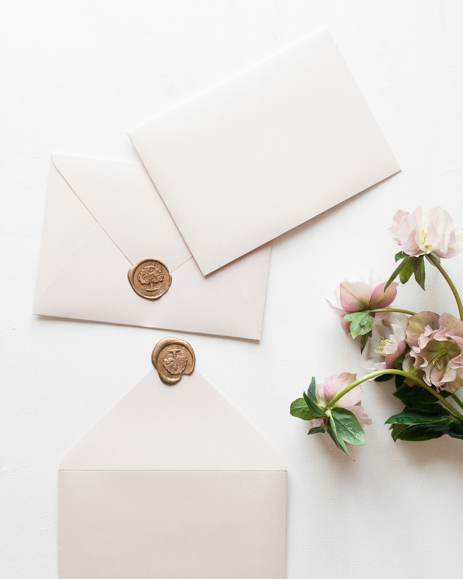 a white envelope with a wax stamp and some pink flowers