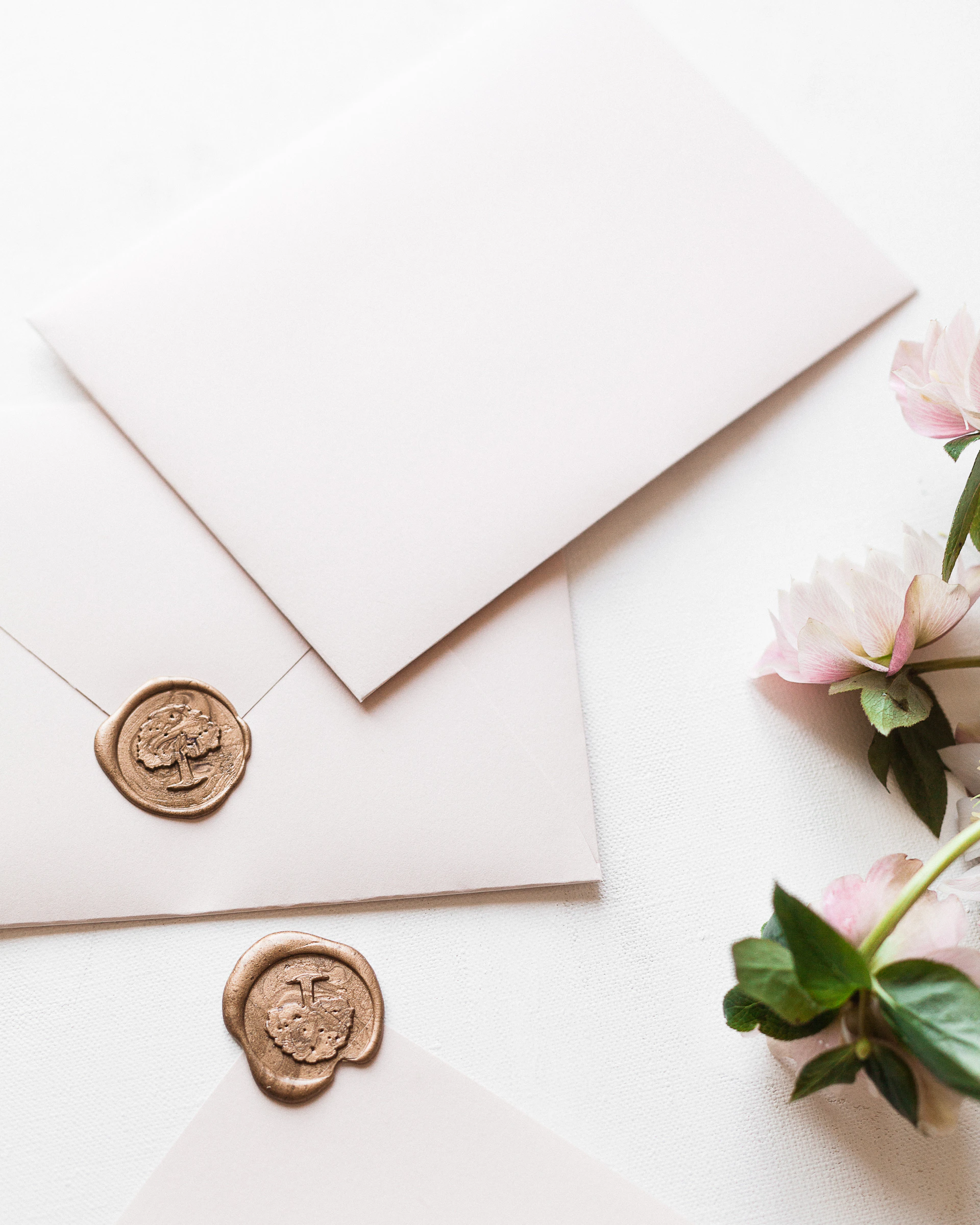 a white envelope with a wax stamp and some pink flowers