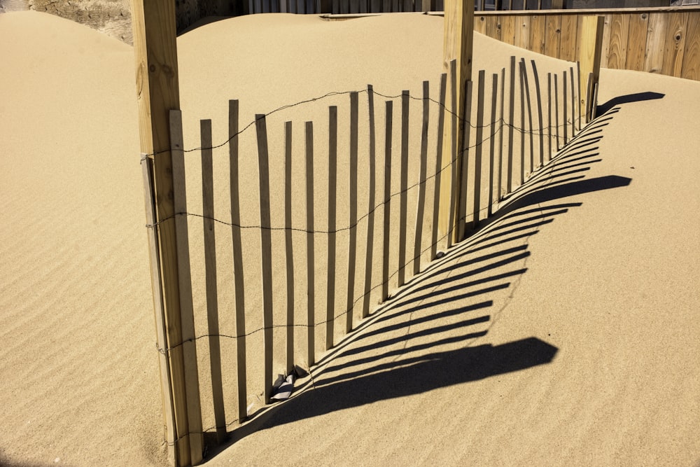 a fence in the sand with a pair of shoes on it