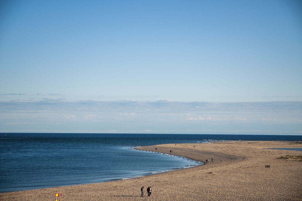 um grupo de pessoas em pé no topo de uma praia de areia
