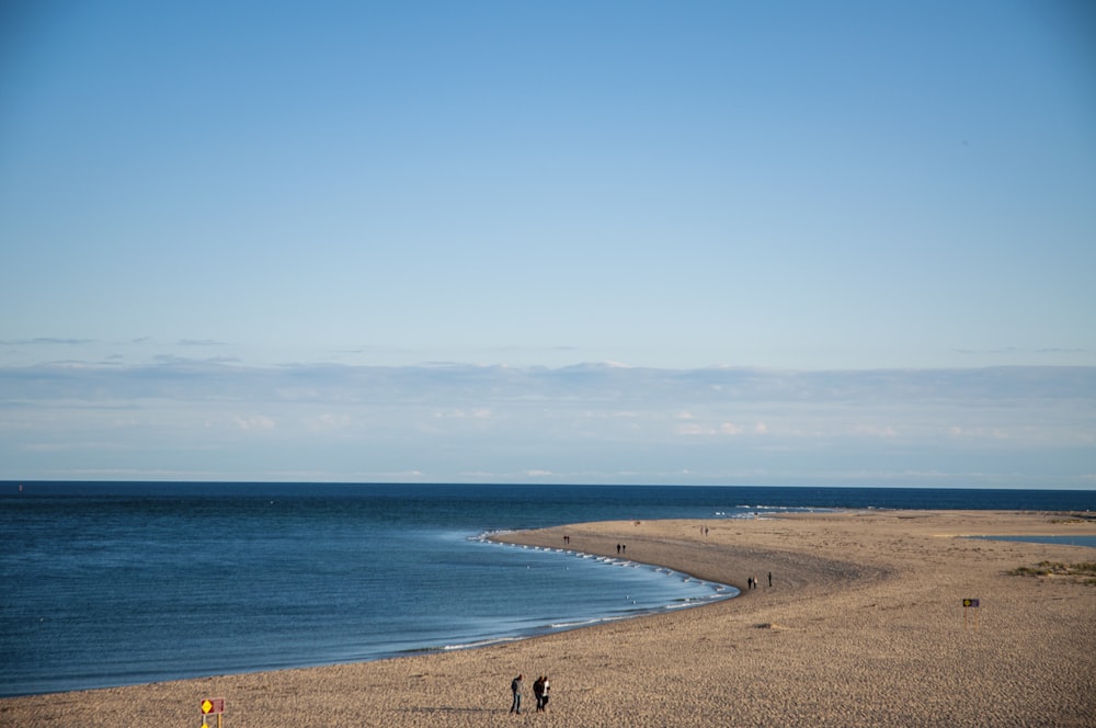 Un gruppo di persone in piedi sulla cima di una spiaggia sabbiosa