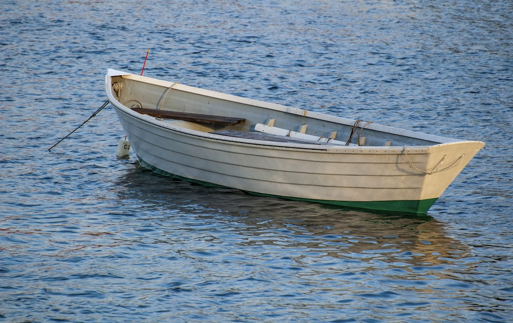 um pequeno barco branco flutuando em cima de um corpo de água