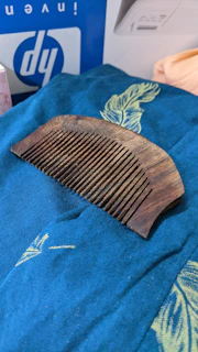 Close-up of a vintage wooden comb resting on a soft linen cloth, sunlight casting gentle shadows.