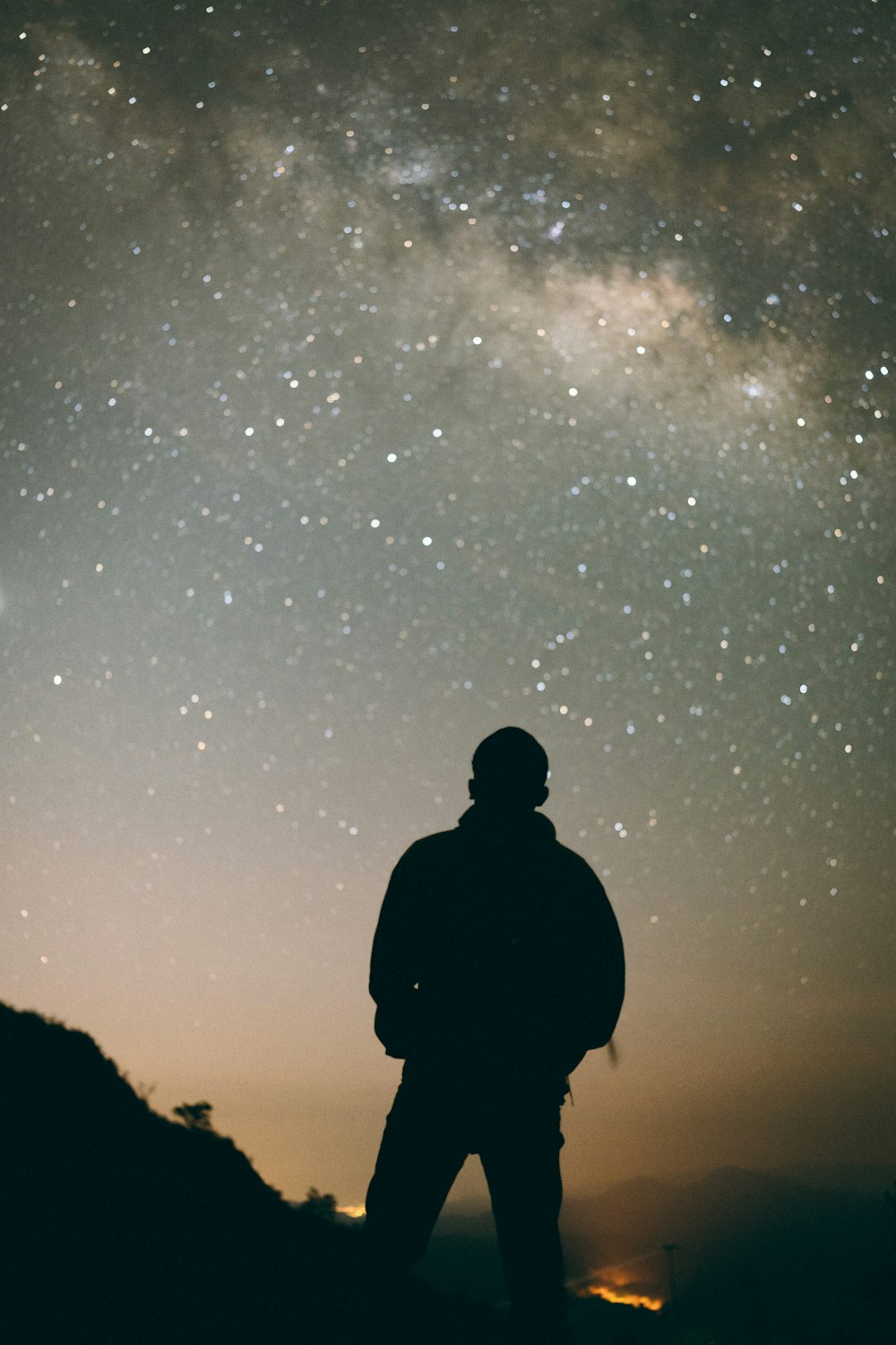 夜空の下の丘の上に立つ男