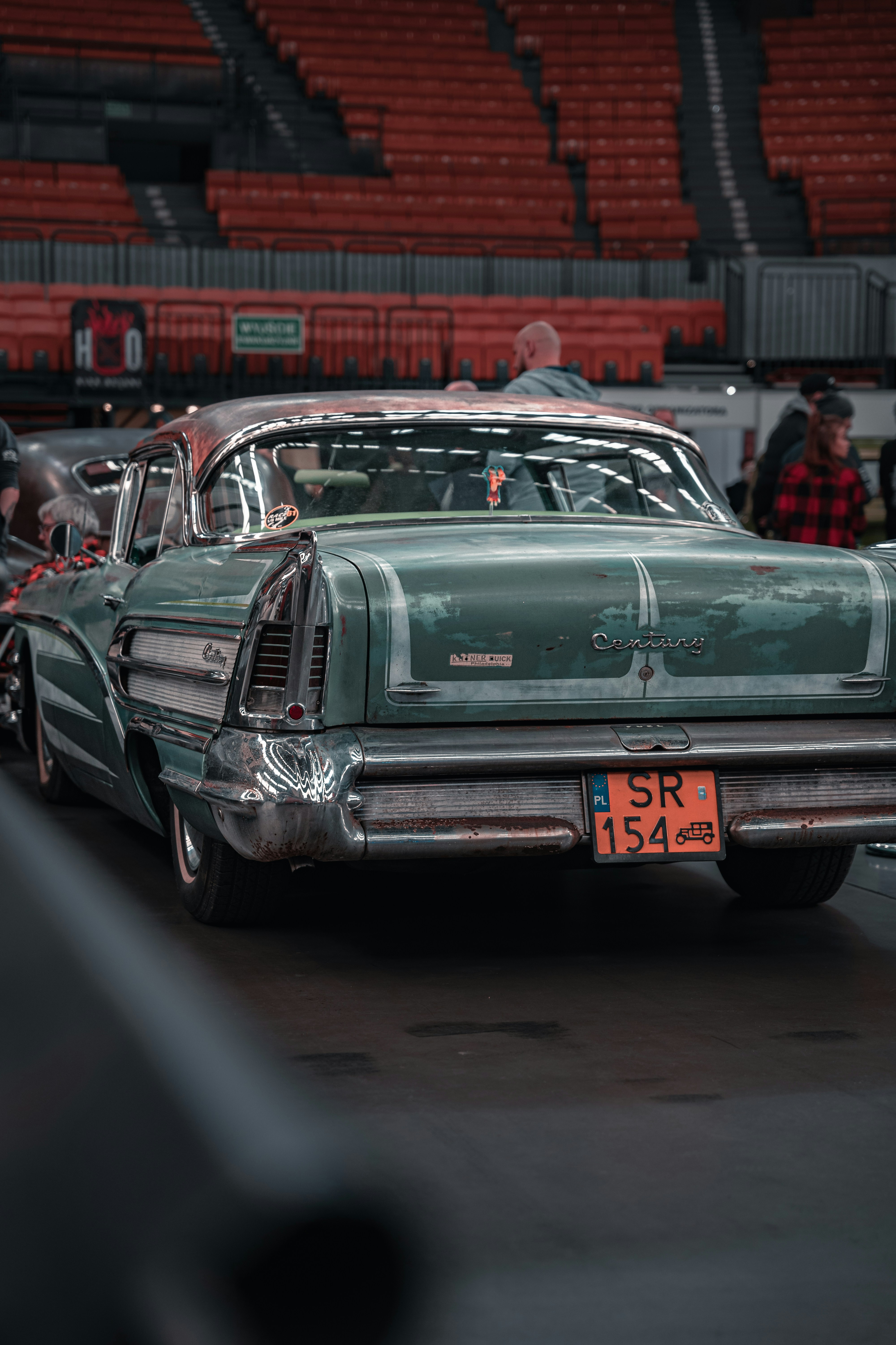 an old green car parked in a parking lot
