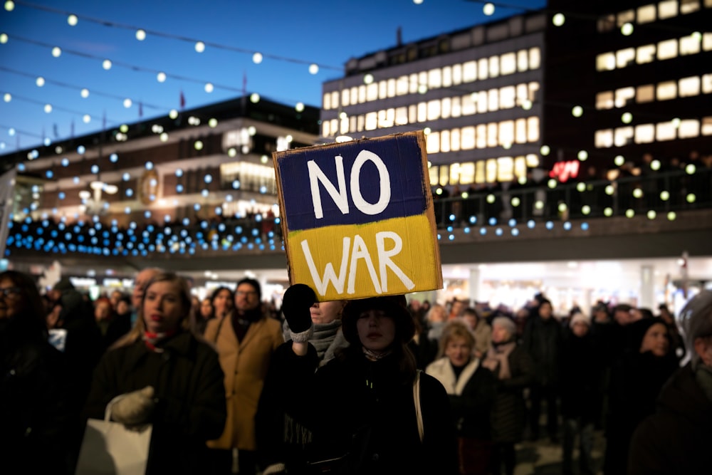 a person holding a sign that says no war