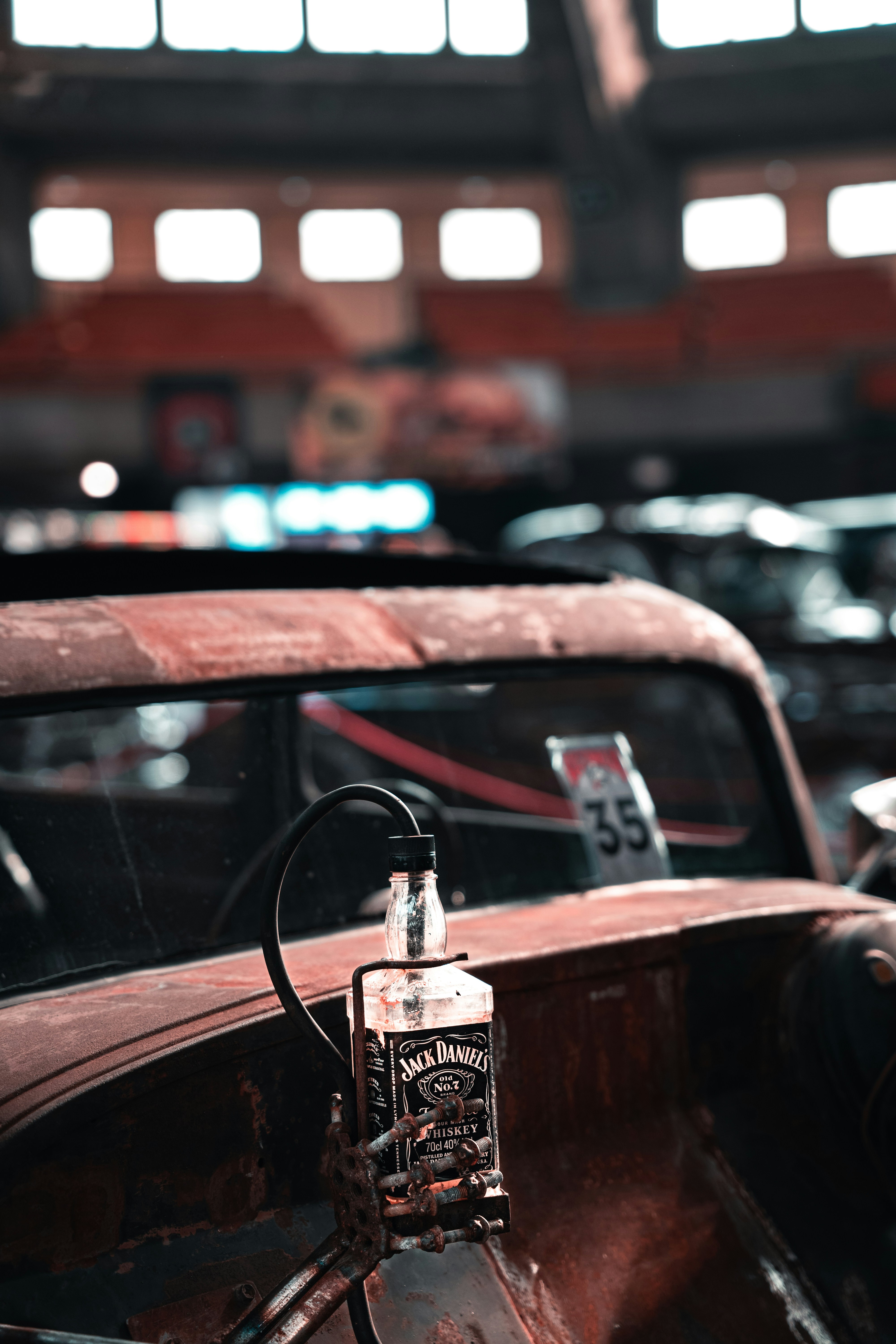 an old rusted car with a bottle of alcohol on the hood