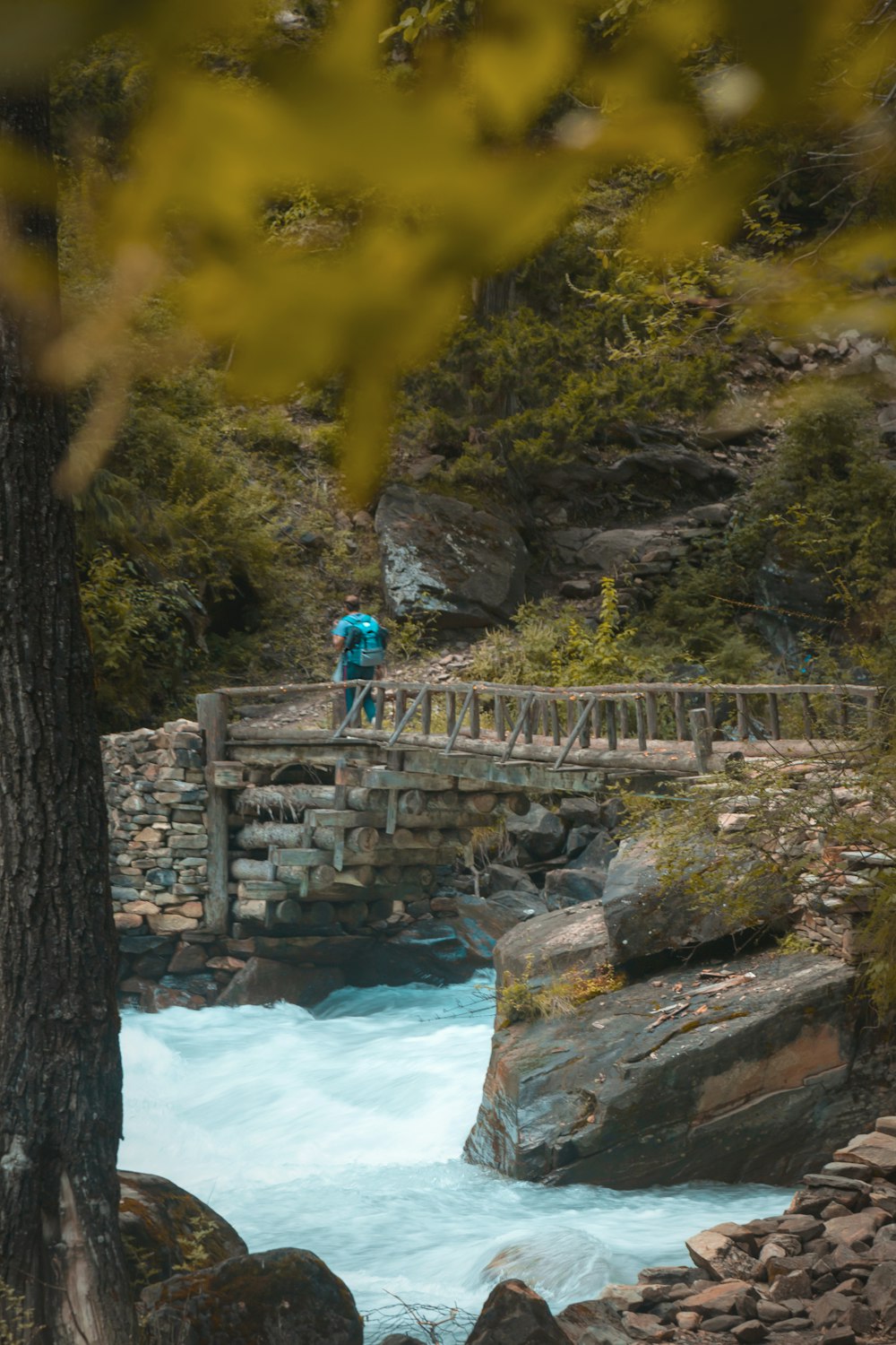 a man walking across a bridge over a river