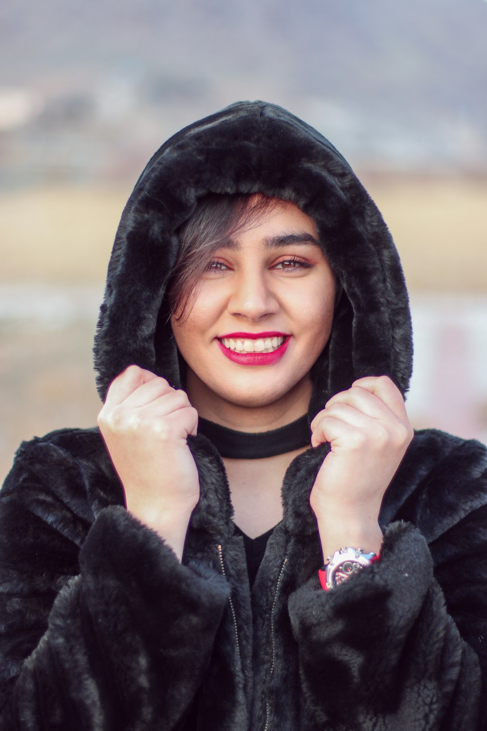 a woman wearing a black hooded jacket and smiling