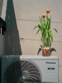a small air conditioner sitting next to a flower pot