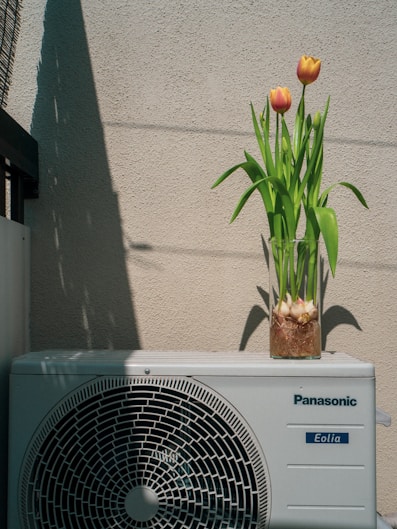 a small air conditioner sitting next to a flower pot