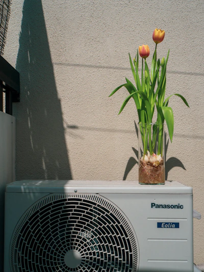 a small air conditioner sitting next to a flower pot