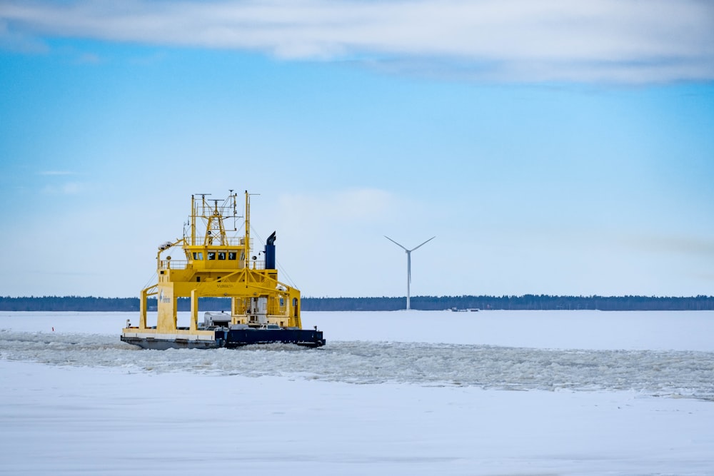 a yellow boat floating on top of a frozen lake