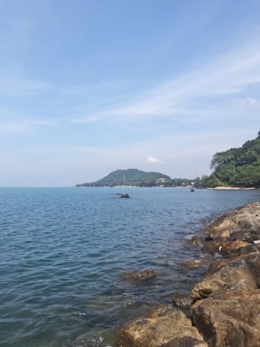 A peaceful coastal view of Cala Rossa with crystal-clear waters and lush greenery under a bright sky